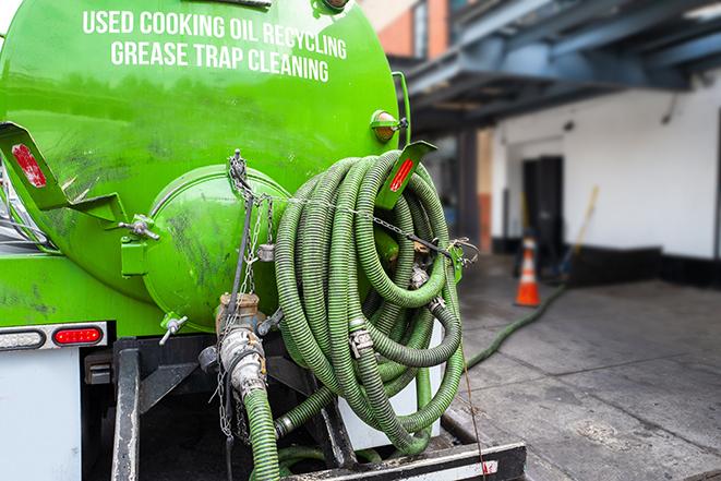 worker pumping grease trap at commercial kitchen in Belle Glade FL